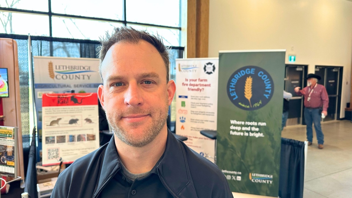 A man stands in front of a booth about Lethbridge County.